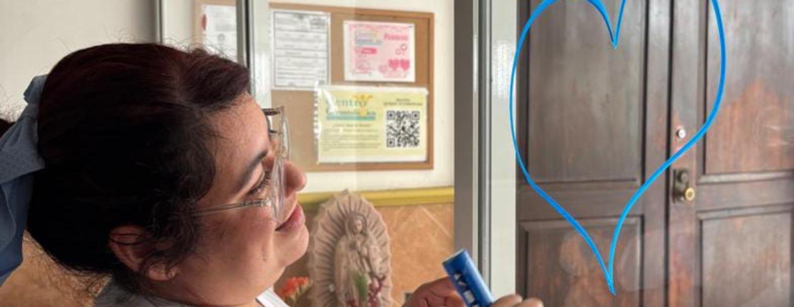 Cuidadora dibujando un corazón en el cristal del centro